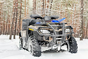 Close-up ATV 4wd quad bike in forest at winter. 4wd all-terreain vehicle stand in heavy snow with deep wheel track. Seasonal extre
