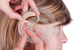 Close up of an Audiologist hands inserting a hearing aid into ea