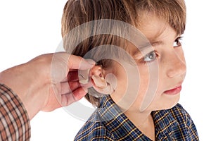 Close up of an Audiologist`s hand fitting hearing aid to a young boy