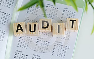 Close-up of audit word collected with wooden cubes in row. Business, accounting and economy concept.