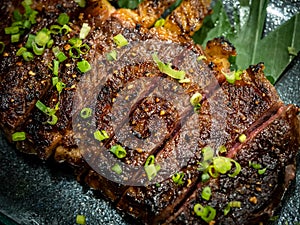 Close-up Australian sliced medium rare wagyu grilled beef steak top with sliced spring onion on glass plate on dark background.