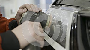 Close up for auto mechanic buffing and polishing car head. light. Art. Worker polishing the headlight of a car at