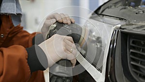 Close up for auto mechanic buffing and polishing car head. light. Art. Worker polishing the headlight of a car at