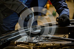 Close-up auto mechanic hands with wrench repairing car in the garage of a repair shop