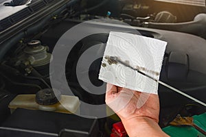 Close up auto mechanic`s hand checks the level and color of engine oil in a car engine during maintenance