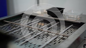 Close up of automated conveyor belt at a factory. Media. Man hands putting plastic small boxes on empty conveyor belt.