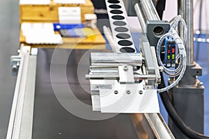 Close up automatic continuous labeling machine for labelling product on belt conveyor in manufacturing process in industrial