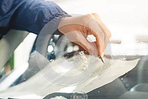 Close up Automobile glazier worker fixing and repair windscreen or windshield of a car in auto service station garage