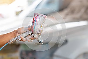 Close up of Automobile repairman painter hand holder a spray paint gun over blurred background, Car repair concept