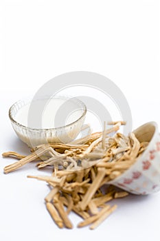 Close up of Ayurvedic herb Satavari or kurilo or Asparagus racemosus isolated on white in a glass bowl with milk.