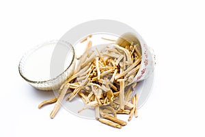 Close up of ayurvedic herb satavari or kurilo in a glass bowl with milk and its powder isolated on white. photo