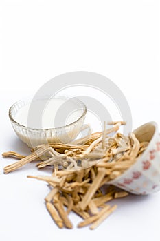 Close up of Ayurvedic herb Satavari or kurilo or Asparagus racemosus isolated on white in a glass bowl with milk. photo