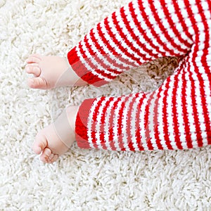 Close-up of baby body and legs in red Santa Clause trousers. New born child, little girl or boy. Kid having fun. Family