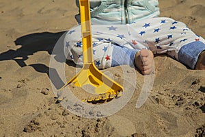 Close up baby boy playing with sand toys at the beach.