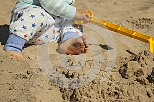 Close up baby boy playing with sand toys at the beach.