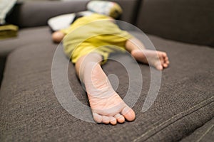 Close-up of a baby boy`s feet sleeping on the couch at his home