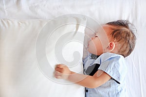 Close-up baby boy sleeping on bed with hugging a pillow