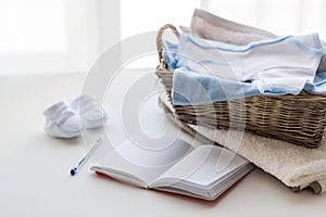 Close up of baby clothes for newborn and notebook