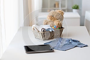 Close up of baby clothes, toys and tablet pc