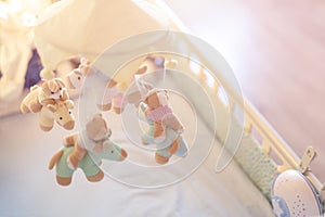 Close-up baby crib with musical animal mobile at nursery room. Hanged developing toy with plush fluffy animals. Happy parenting an