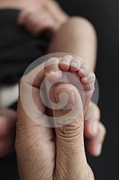 Close up baby feet in mother hands on black background. Mother is doing massage