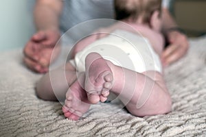 Close up of a baby feet. Mother`s hands in the foreground. Childcare concept. Selective focus