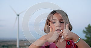 Close-up of a baby girl showing against the background of windmills.