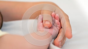 Close up baby hand holding finger mom in a room with a lot of sunlight. Newborn