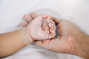 Close up baby hand on mother`s hands  in sun light