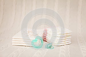 Close up baby hygiene items. stack of diapers, ear sticks, baby dummy and teether in selective focus