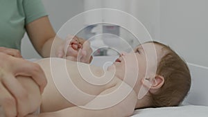 Close up of baby lying on changing table and holding hand of mother