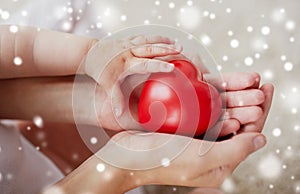 Close up of baby and mother hands with red heart