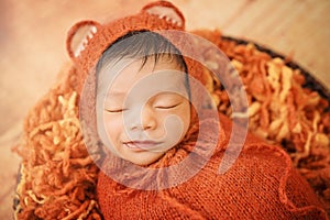 Close up Baby newborn wearing fox mohair bonnet and orange brown swaddling wrap