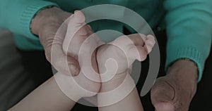 Close-up of a baby`s feet in the wrinkled hands of a grandmother.