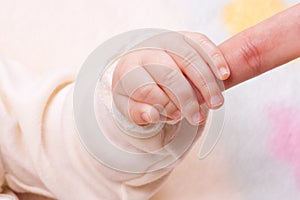 Close-up of baby's hand holding mother's finger