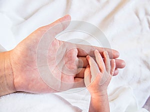Close-up of baby`s hand holding mother`s finger with tenderness