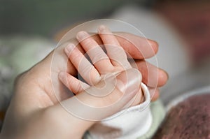 Close up baby`s hand put on mom`s hand. Mom nursing baby. mom and baby boy relax at home. Nursery interior. Mother breast feedin