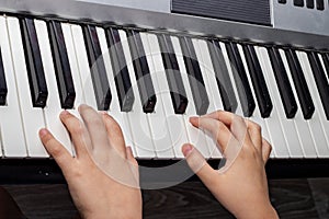 Close up of baby`s hands playing the piano. Hands of a child playing the keyboard of a synthesizer. A closeup image of a baby`s