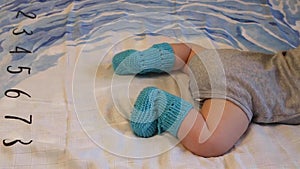 Close-up of the baby`s legs in knitted Booties on the bed