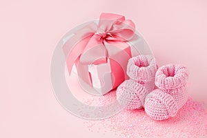 Close up of baby shoes, present gift box - sweetness and baby booties on pink background, first newborn party background, birthday