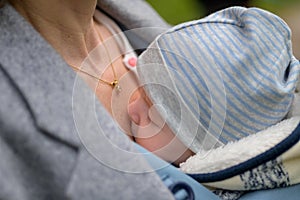 Close up of a baby sleeping in a baby carrier, in an extraordinary closeness to his mother photo