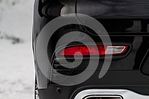 Close up back light of the modern black car. Rear car stop lights on car bumper.