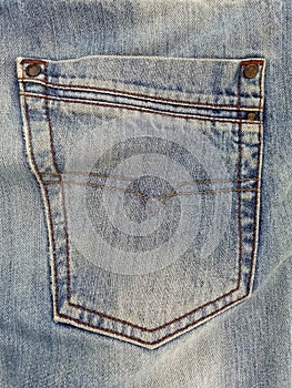 Close up of back pocket of blue jean pants. Blue jeans pattern. Used jeans texture. Clothes and fashion concept