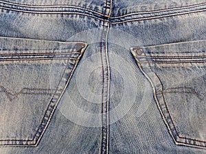 Close up of back pockets of blue jean pants. Blue jeans pattern. Used jeans texture. Clothes and fashion concept