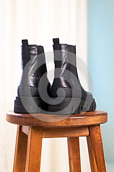 Close-up back side of black elegant shoes on wooden background. Leather winter boots, stylish lady footwear concept