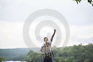 Close up back of tourist girl with arms raising happy with nature near lake.