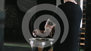 Close-up back view male weight lifter athlete applying talc powder before exercising in large hardcore gym hall.