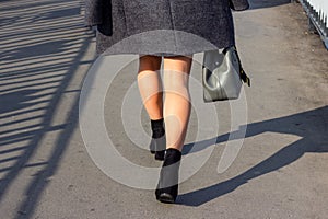 Close up back view of a pretty young woman legs walking down the street in the autumn on a modern city background.