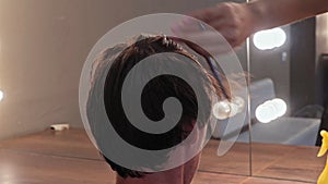 Close up of the back of the young man head with a hairdresser hand with scissors leveling the length of his hair against