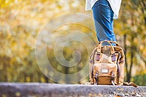 Close up backpack of woman backpacker standing on countryside road with tree in autumn fall seasonal,Alone travel or single